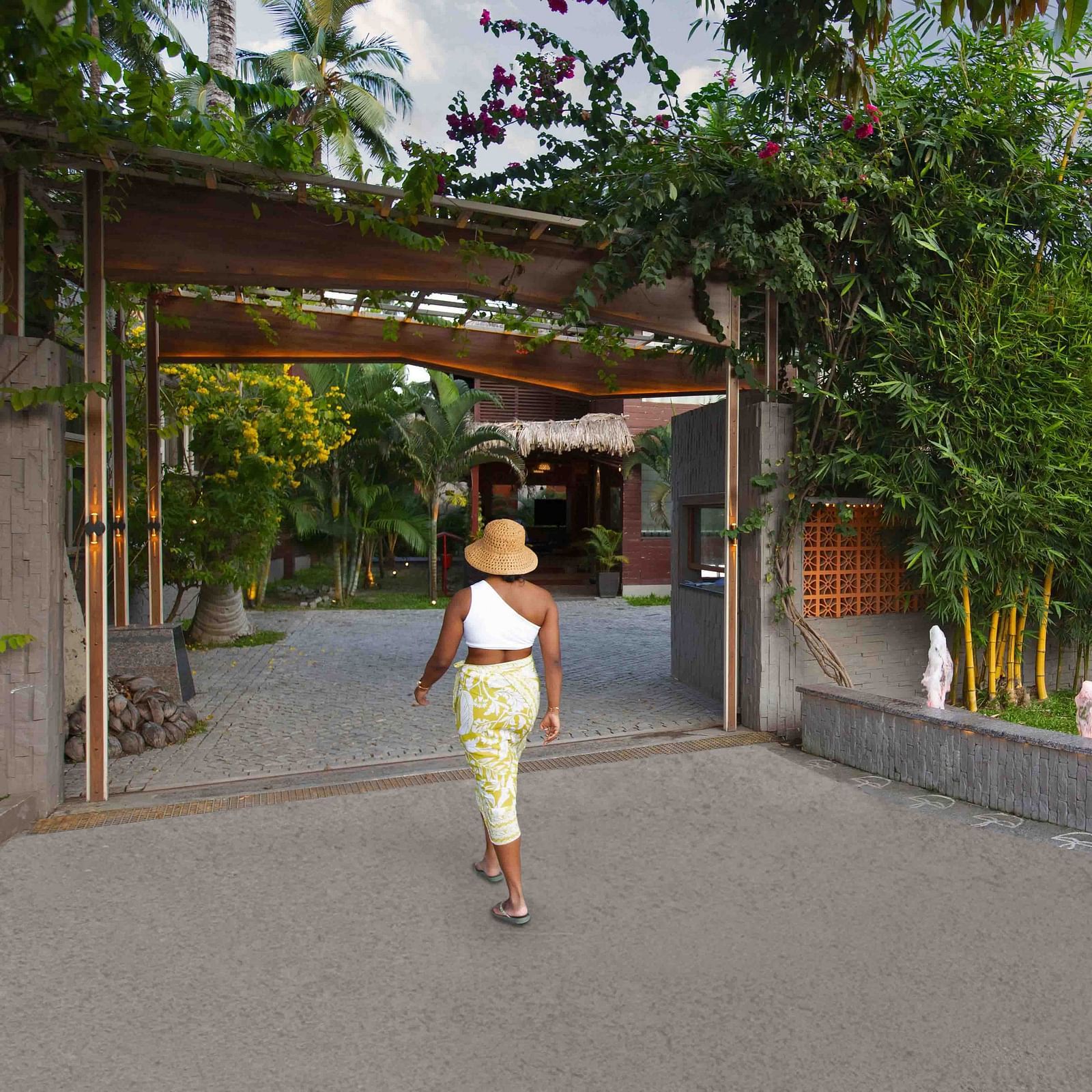 A woman walking towards the entrance of the Coral Reef Hotel & Resort wearing beachwear.
