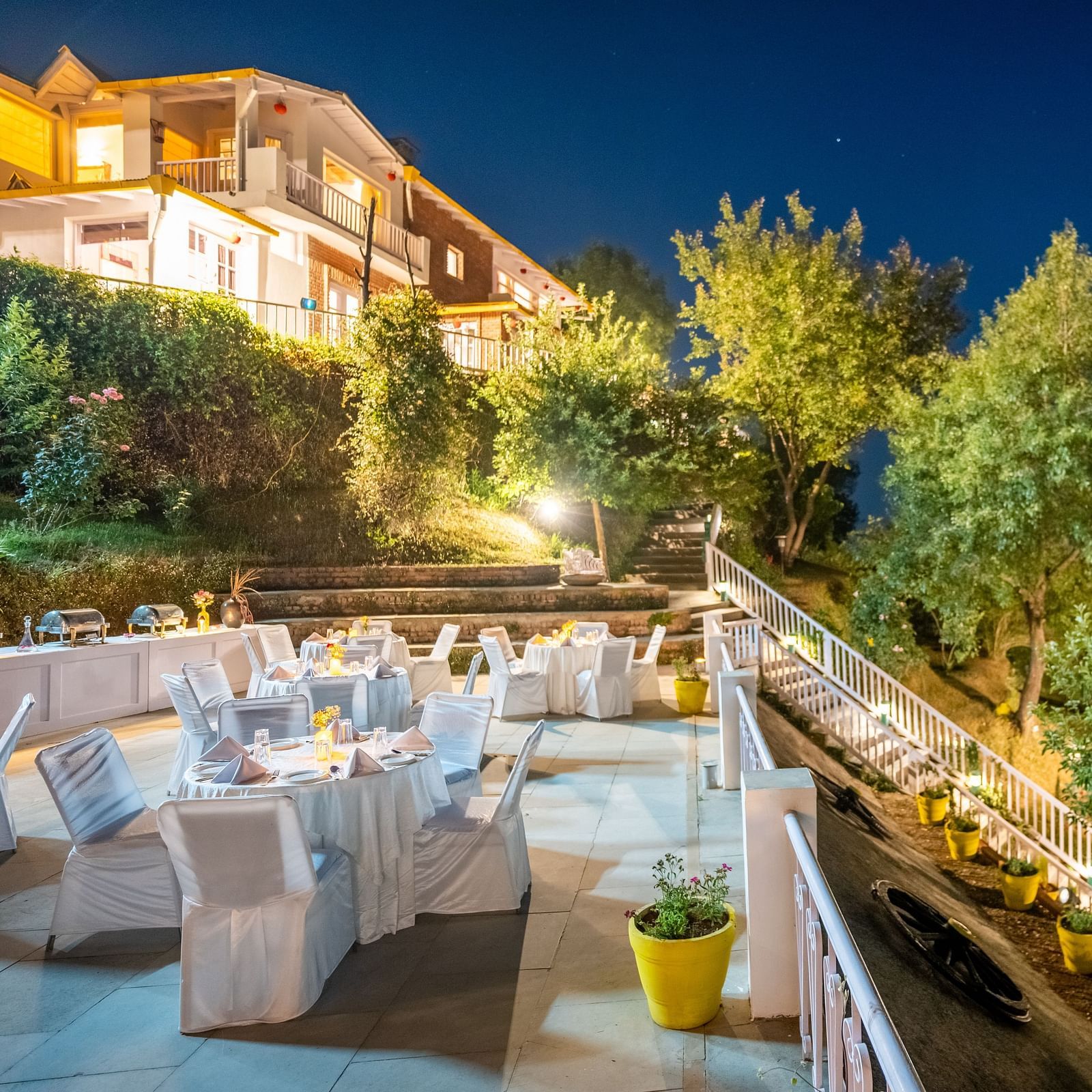 A terrace with a dinning space surrounded by trees at Te Aroha By Shervani, Mukteshwar