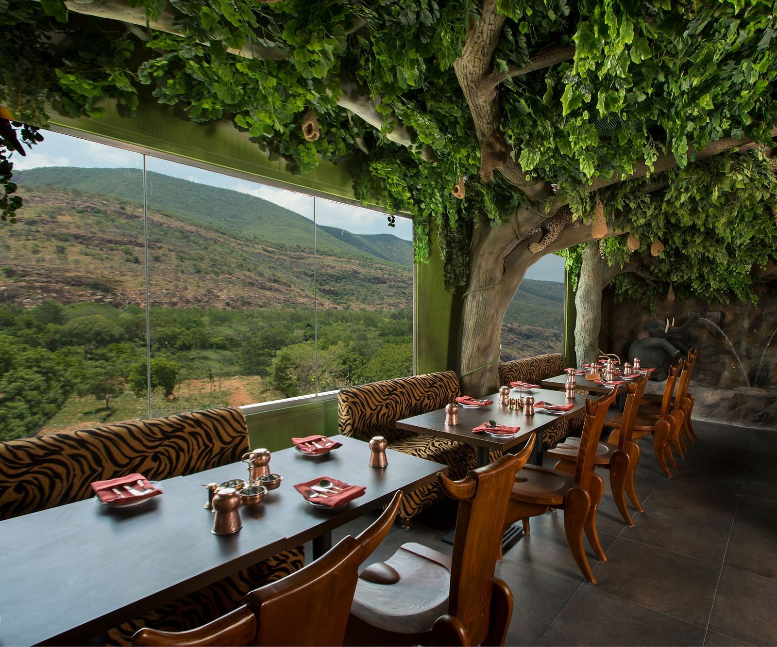 Seating arrangements in front a floor to ceiling glass windows at Gufha Restaurant -Hotel Pai Viceroy Tirupathi