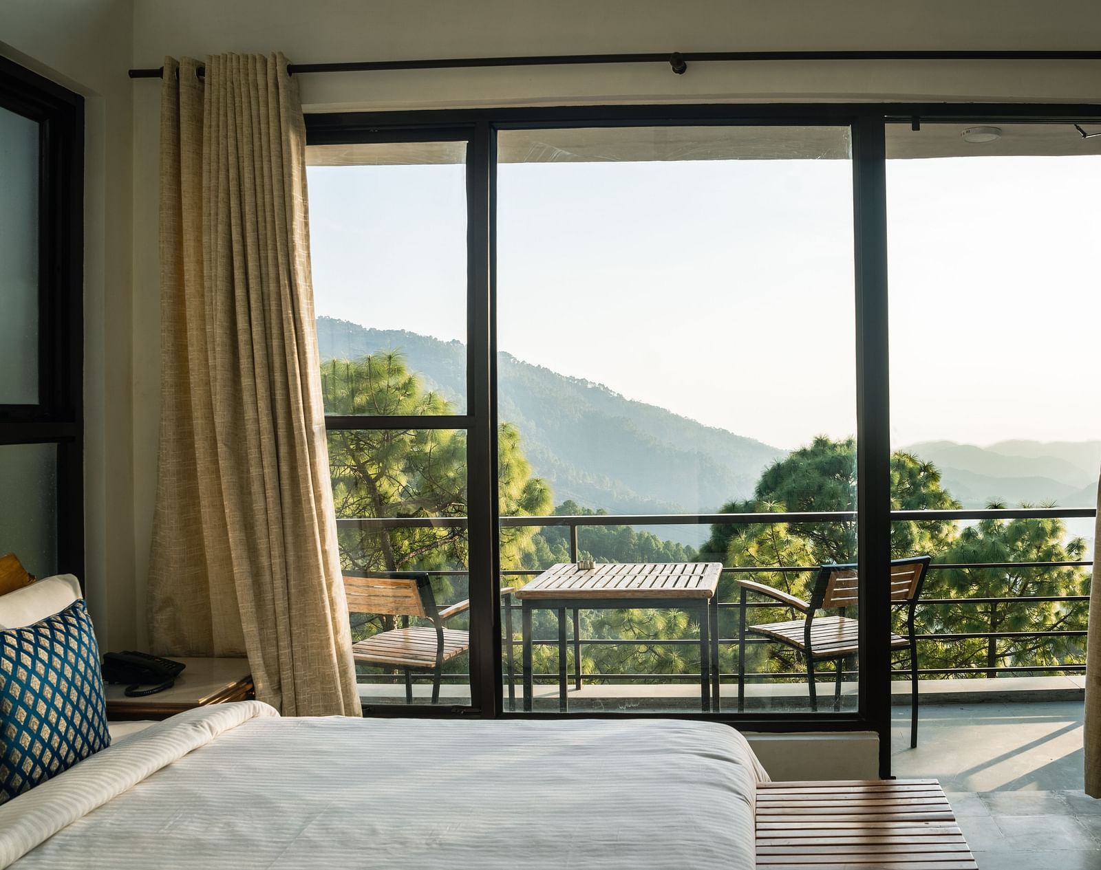 A bedroom with a balcony offering natural light and scenic views at BluSalzz Escapade Resort, Lansdowne