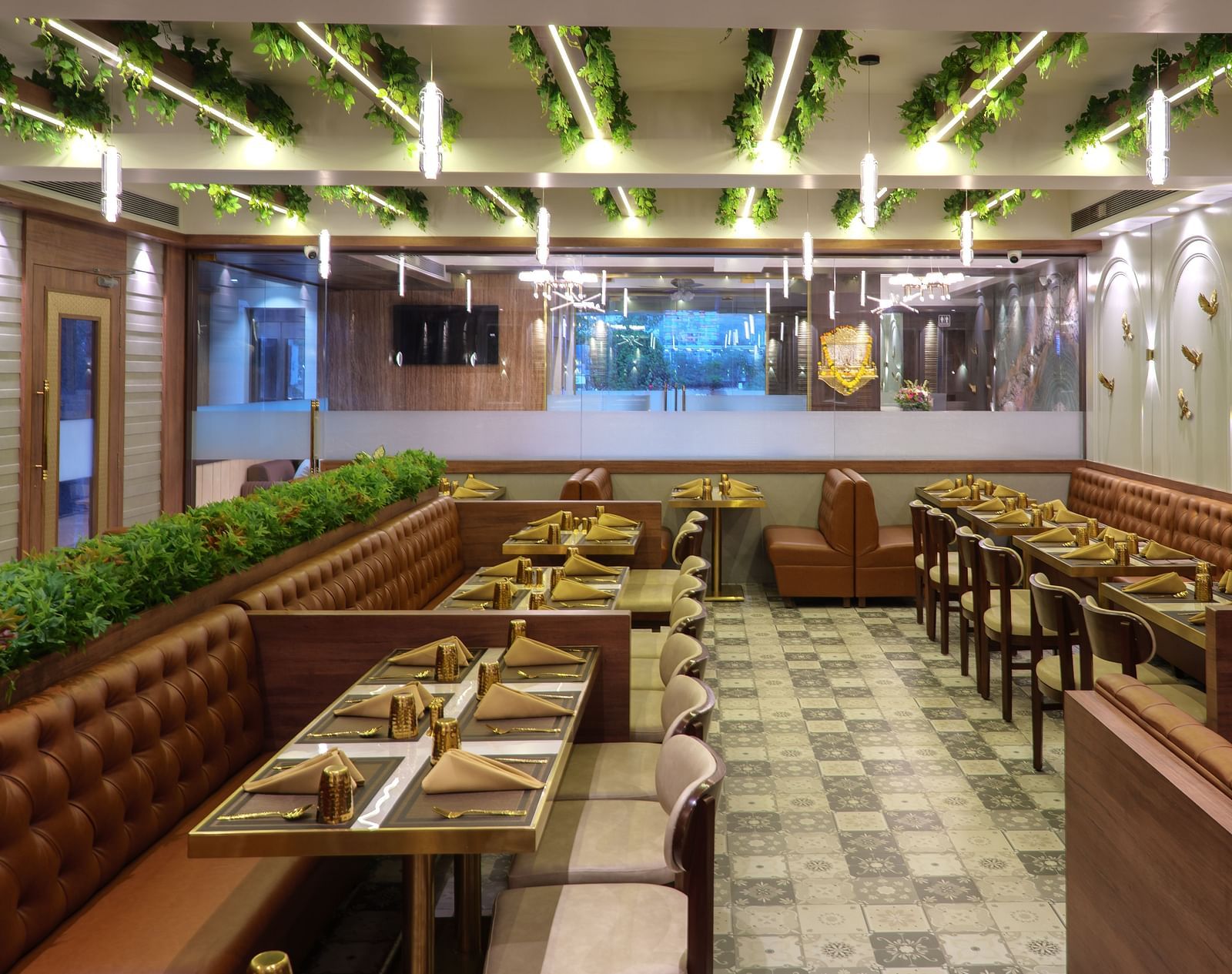A spacious restaurant with numerous wooden tables and chairs, featuring bright overhead lighting and some greenery - Melior Inn