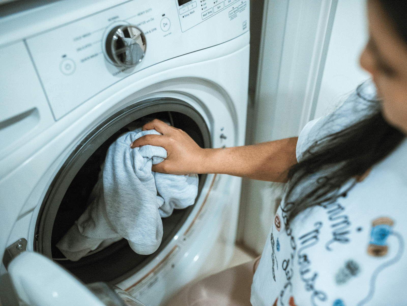 Guest using laundry service with clothes being placed in a washing machine for cleaning.