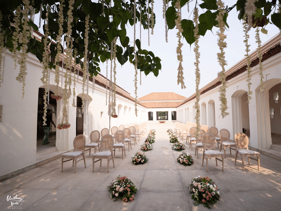 A wedding lawn at Marasa Sarovar Premiere Bodhgaya featuring sets of chairs on either side and a pathway in between where bouquets are placed.