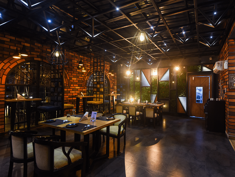 The interiors of TOB has a rustic ambience with bricked walls and mellow lighting - Wedlock Greens Hotel Resorts Dhanbad