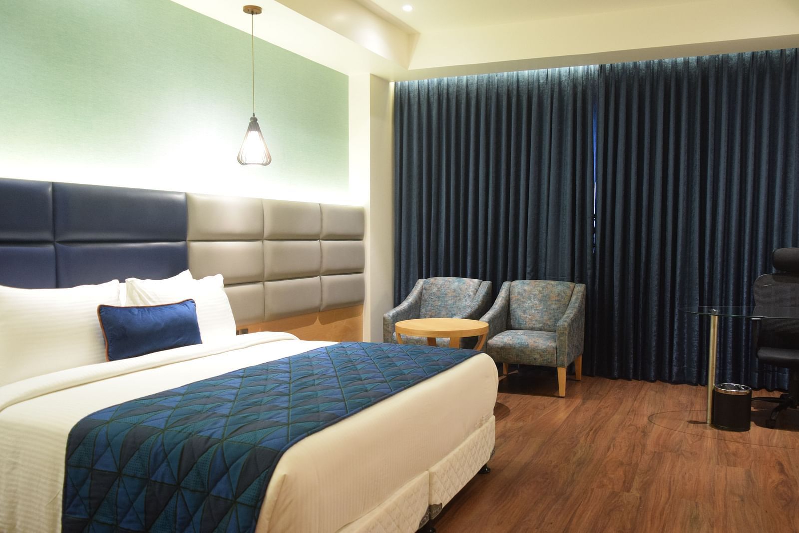 A comfy premium room with king size bed , chair at SRM Hotel Maram Malai Nagar, Chennai
