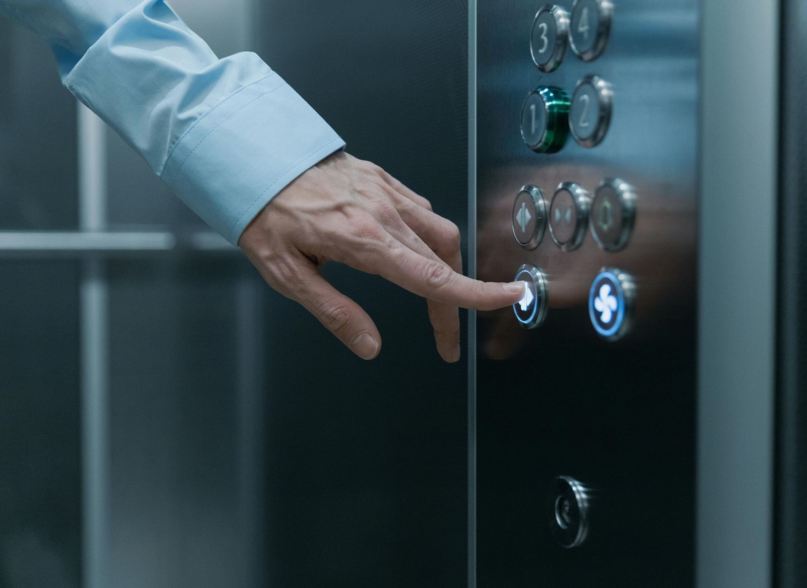A close up shot of the hand of a man pressing an elevator button