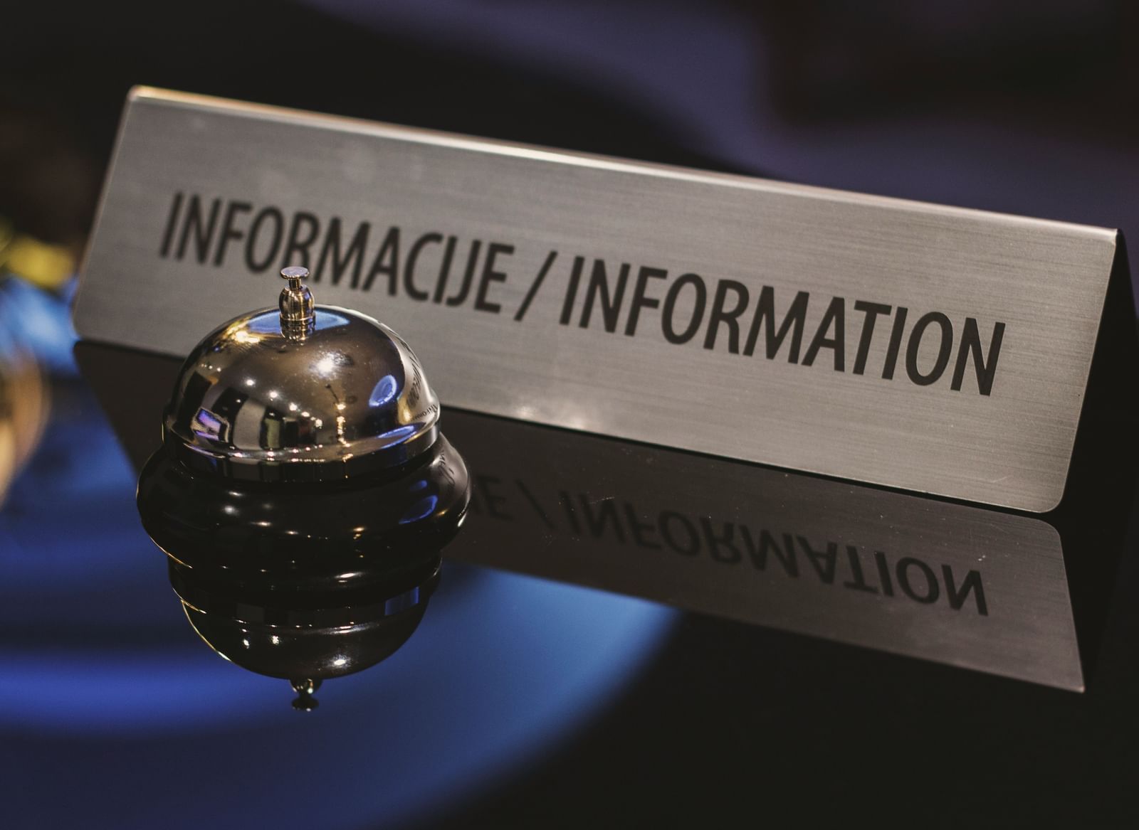 Hotel reception desk with a service bell and an information sign.