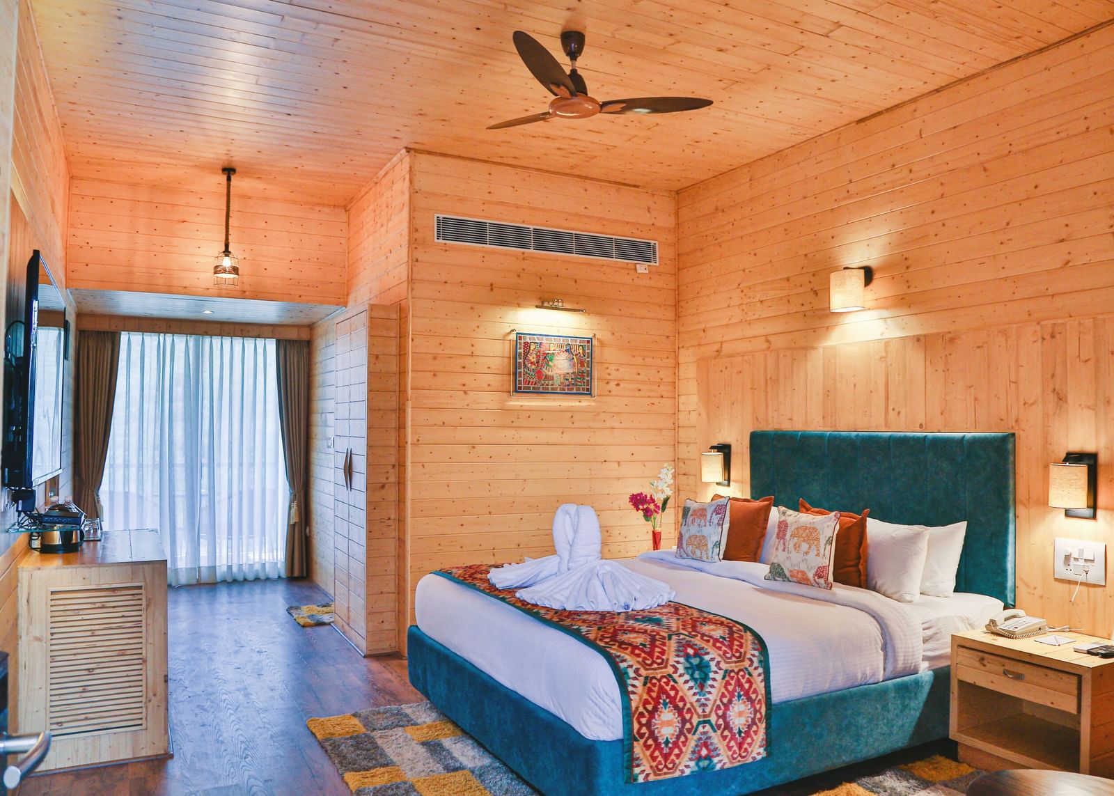 A cosy bedroom with wooden paneling, curtains, a plush bed and warm lighting. - Bamboo Saa Resort & Spa, Udaipur