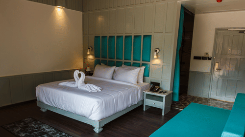 A double bed with dove towels, side stand, and lamps inside the hill villa room at Symphony Samudra Beachside Jungle Resort And Spa | Port Blair Villas