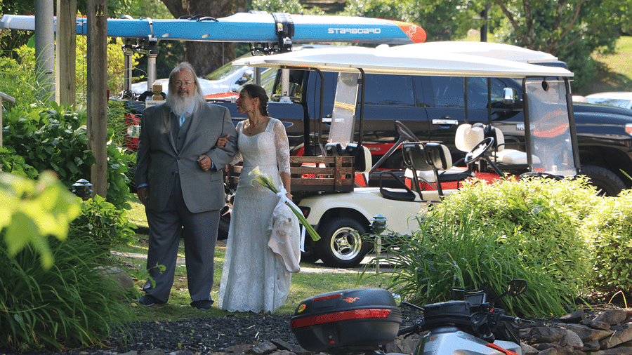 a father along with his daughter dressing in a white wedding gown and a golf cart behind them - Historic Tapoco Lodge