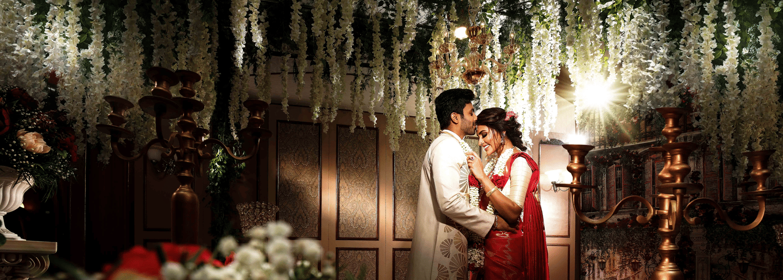 An image of a wedding photo shoot where a groom kissing a bride's forehead.
