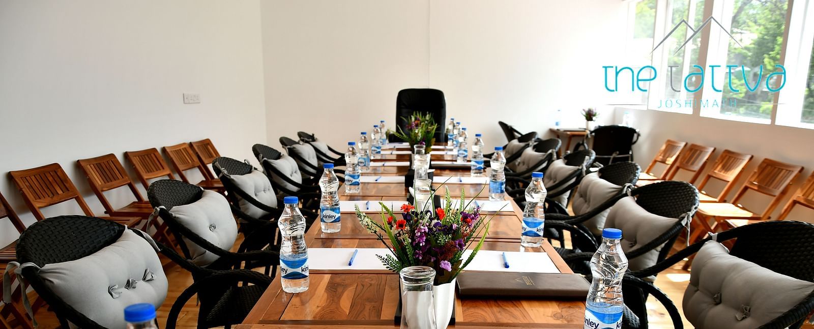 front view image of the conference hall featuring the expansive table decorated with flowers and stationery at the tattva, joshimath