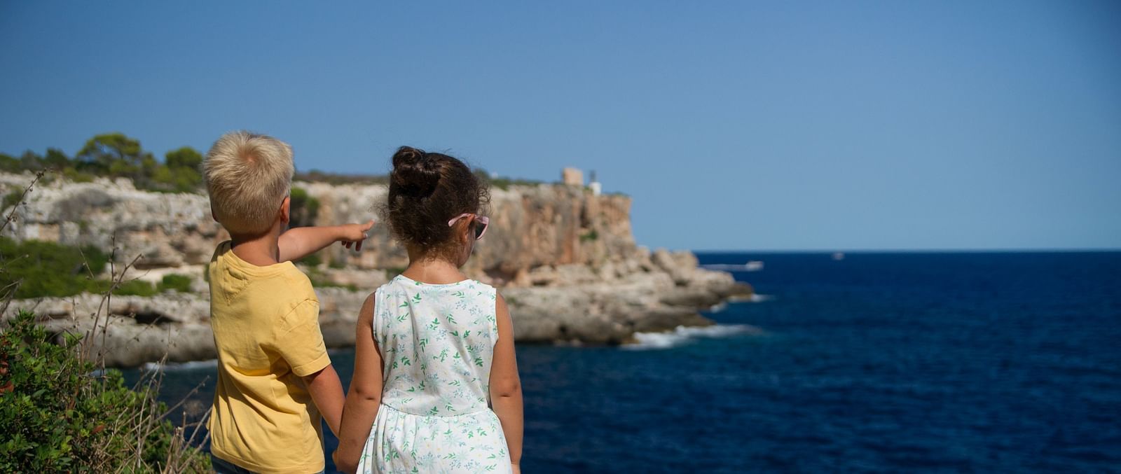 Two kids enjoying a serene view of a deep blue sea on a sunny day