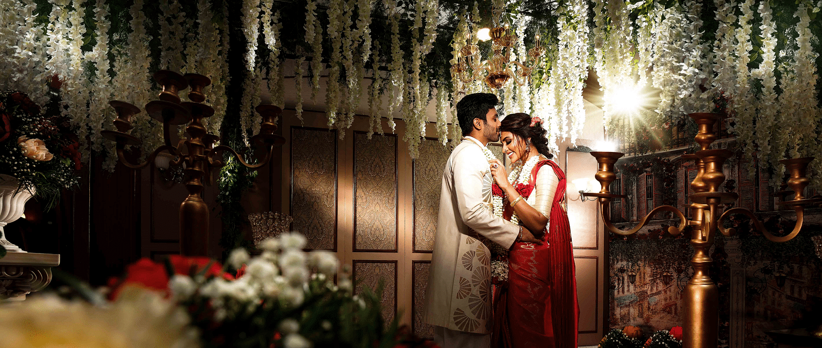 An image of a wedding photo shoot where a groom kissing a bride's forehead.