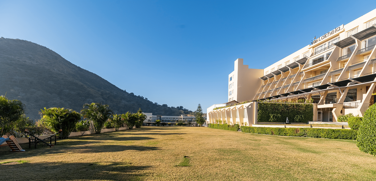 A wide shot of a building with a mountain backdrop - Via Lakhela Resort & Spa