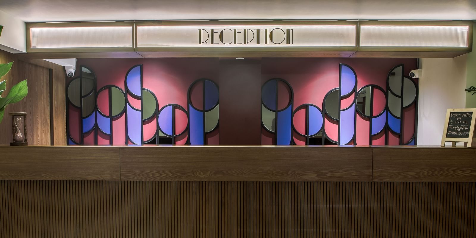 The reception desk at T24 Retro Hotel , with a colourful geometric design behind it  | T24 Retro