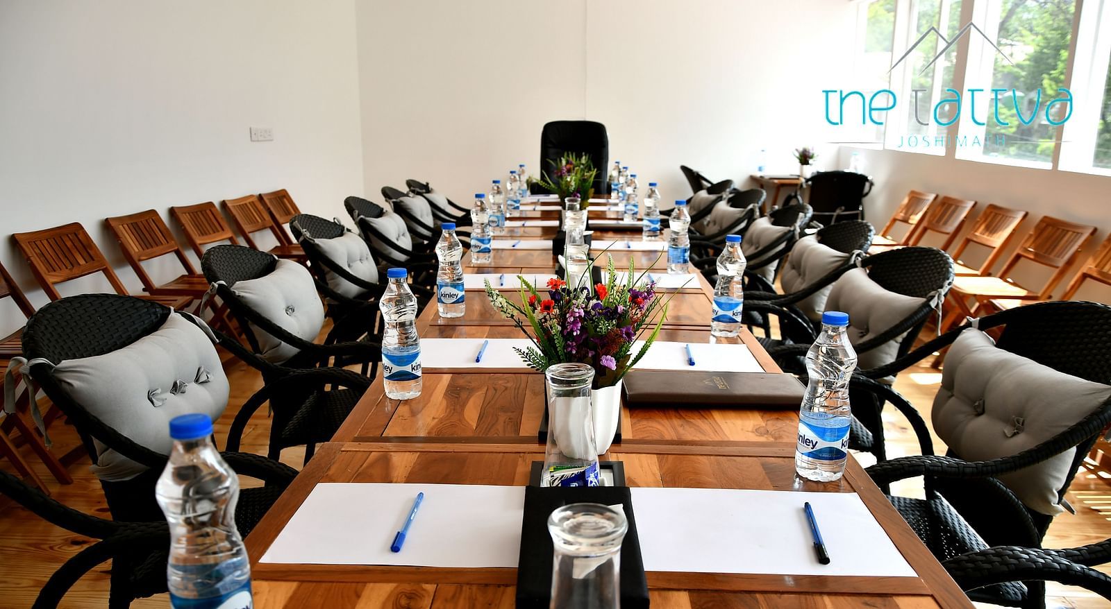 front view image of the conference hall featuring the expansive table decorated with flowers and stationery at the tattva, joshimath