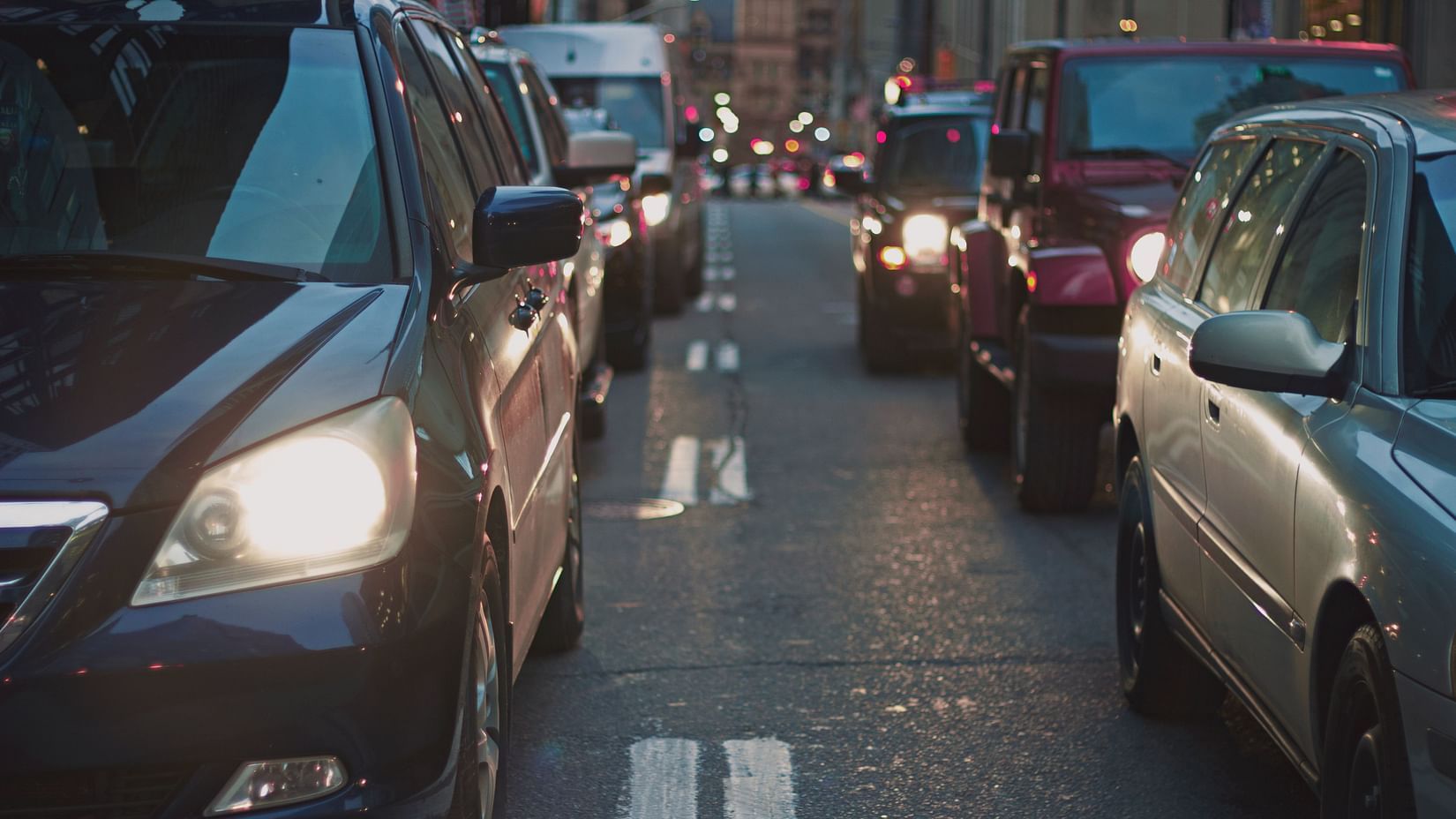 a bunch of cars standing in a rows on a road
