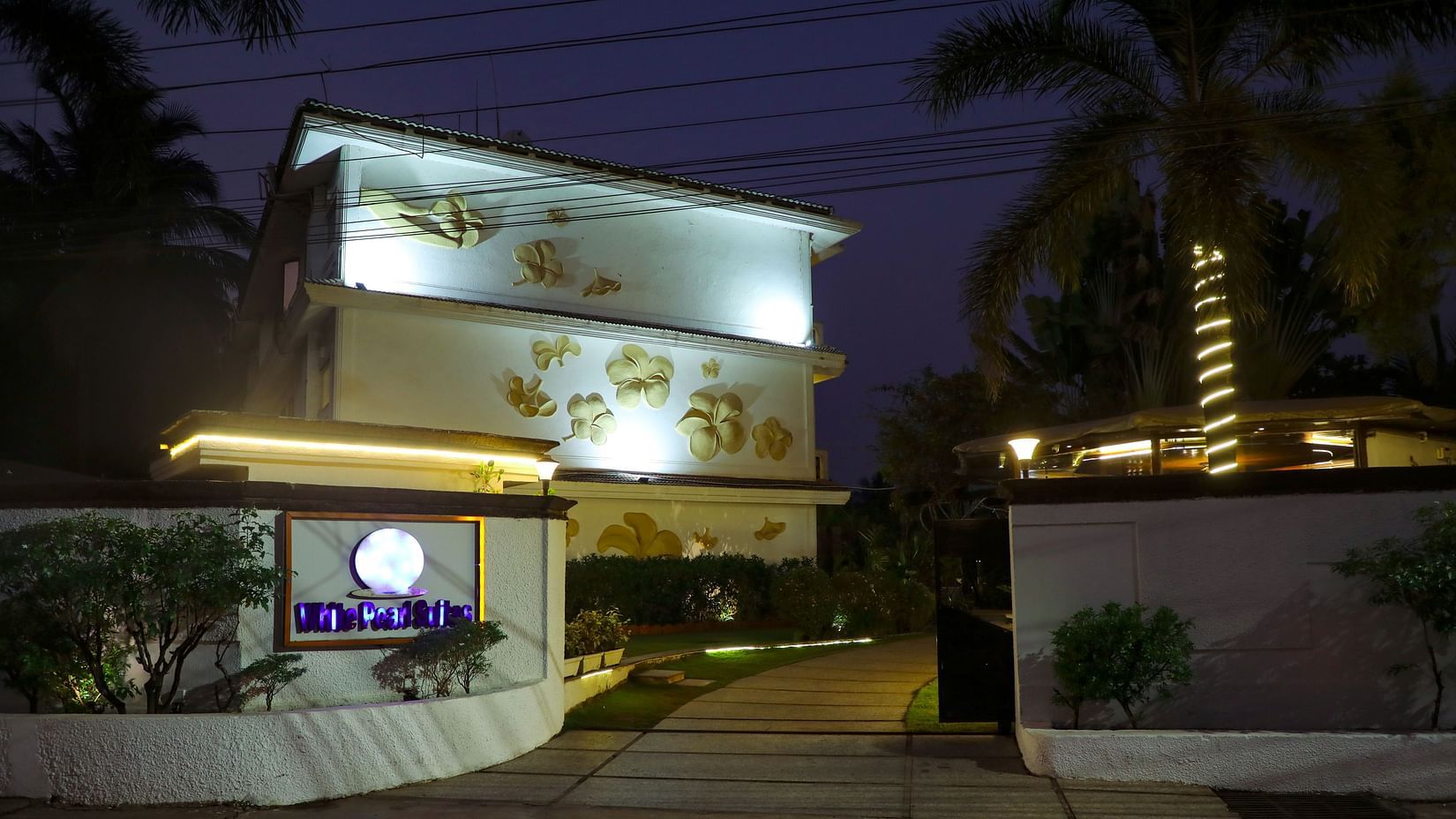 facade of White pearl suites by rosetum in the night with the lights on.