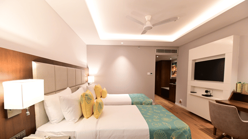 A room at Golden Tulip Vagator, Goa with twin beds, a television and a work desk and chair set up