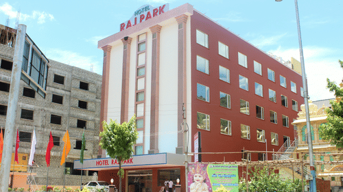Facade of Raj Park Tirupati, showcasing a modern red-and-white exterior with a welcoming entrance in the heart of the city.