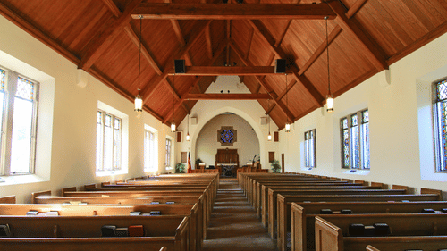 Interior of a church with pews and a stained glass window.