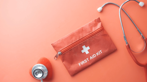 First aid kit with a stethoscope placed beside it on a surface.