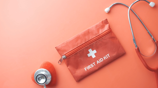 First aid kit with a stethoscope placed beside it on a surface.
