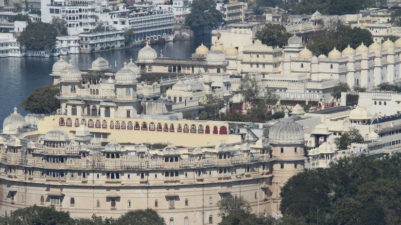 A far out view of the City Palace with other buildings and trees in view.