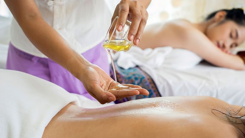A masseuse applying oil to a guest