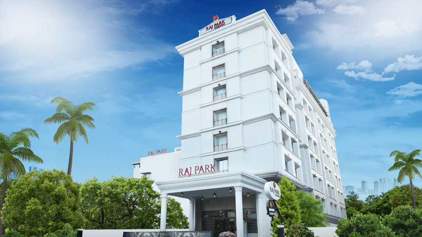facade image of Raj Park Hotel, Chennai with trees on either side and blue sky in the background