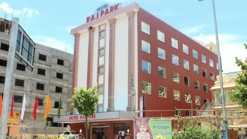 Facade of Raj Park Tirupati, showcasing a modern red-and-white exterior with a welcoming entrance in the heart of the city.