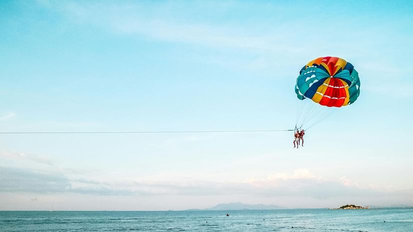 Person Riding Parachute Above Ocean