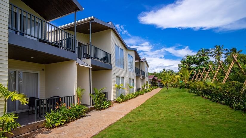 facade image of the sibaya beach resort, morjim beach with a serene green lawn in front of it
