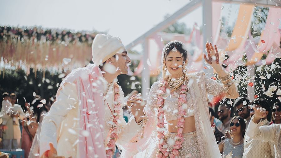 A bride and groom wearing garlands during their wedding ceremony, surrounded by vibrant decorations and smiling guests