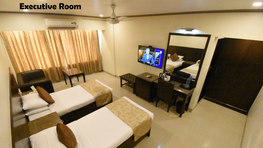 A bedroom featuring 2 twin beds, a big vanity, a flat screen TV, a sofa and a coffee table | Kings International Juhu