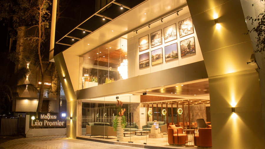 The exterior view of the illuminated entrance and glass facade at Magnus Lxia Premier, Kalyani Nagar at night.