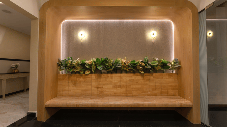 Wooden recessed bench with integrated greenery and wall sconces at Rivido - Manyata.