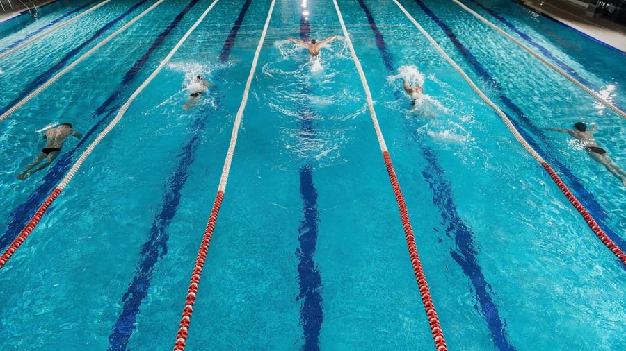 Asian Swimmers competing in a championship event in a six-lane outdoor swimming pool.