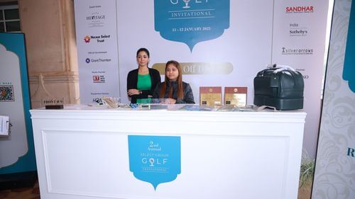 An image of two women sitting behind a desk which has Annual select group for golf written at Heritage Village Resorts & Spa