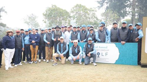 An image of a large group gathered together with a golf celebration board on the golf course - Heritage Village Resorts & Spa