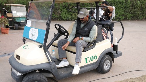 A person with a cap on him sitting on a golf cart. - Heritage Village Resorts & Spa