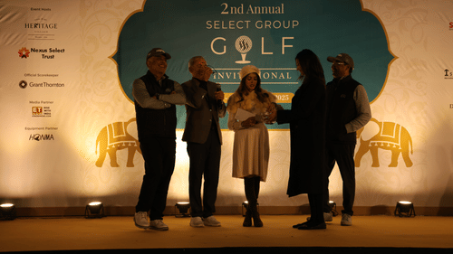 Five people standing on a stage attending an event. - Heritage Village Resorts & Spa