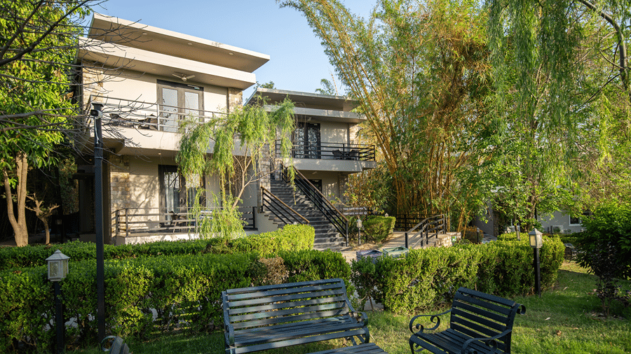 Lawn area of the resort building with a lush green garden and outdoor seating in the daytime at The Golden Tusk, Jim Corbett