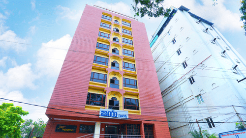 A facade image of Hotel Jaya Residency, Kakinada featuring a multi storey building and in front of it there are cars parked
