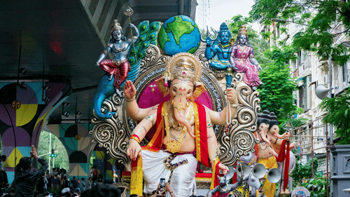  Ganesh Idol taken in an procession with a lot of people gathered around 