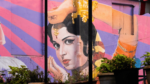 A colourful wall mural depicting a traditional Indian classical dancer with expressive eyes, ornate jewellery, and graceful hand gestures against a vibrant backdrop.