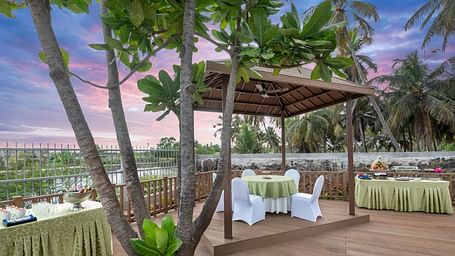 Banquet setup under palm trees with a scenic outdoor backdrop at GRT hotel