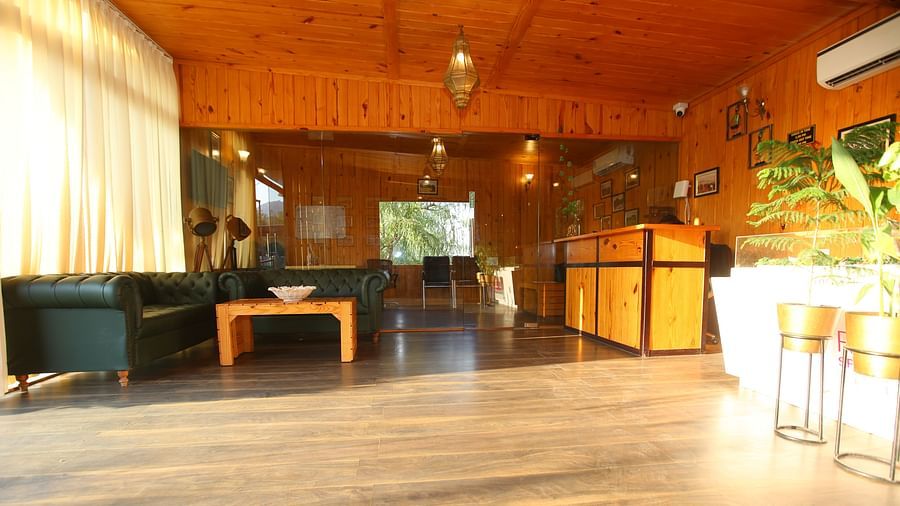 Reception area at Aanandam Resort & Spa featuring a large cozy sofa in the corner and a help desk on the opposite side