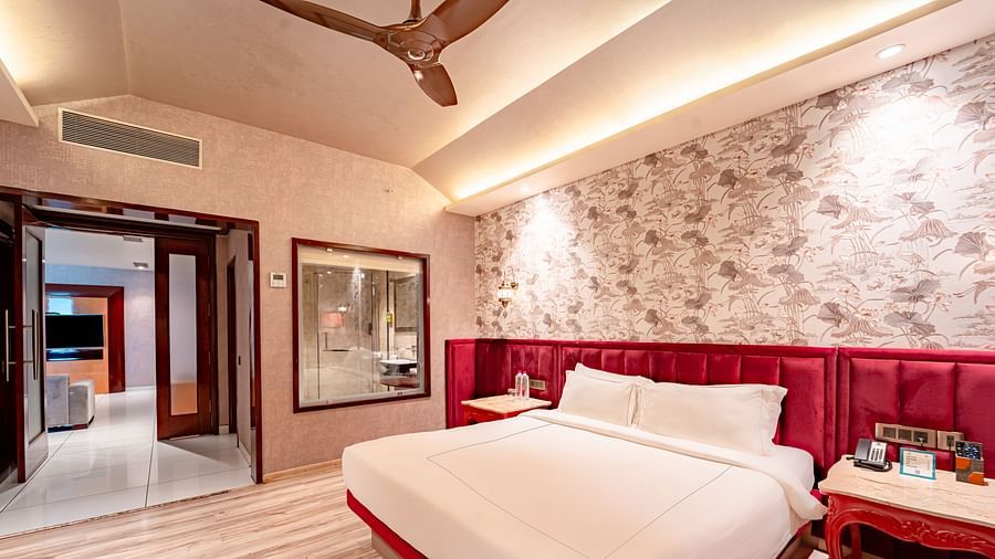 Executive Suite features a spacious bed with a bedside table, warm lighting, and a pathway leading to the next room at Crescent Spa & Resort, Indore
